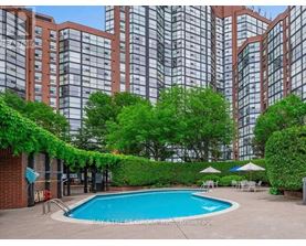 A pool surrounded by greenery and trees in front of a building.