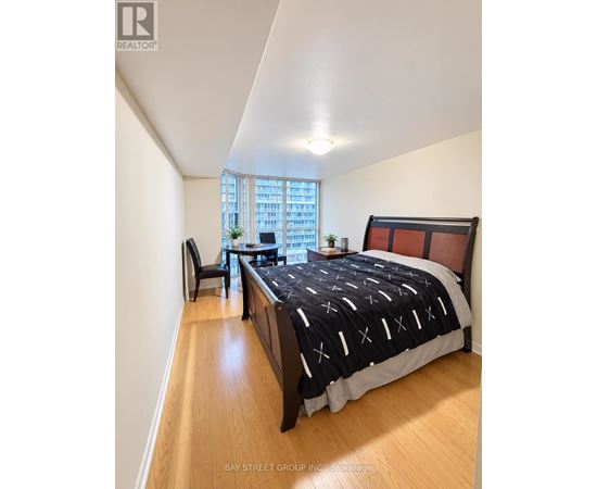 A bedroom with a large bed and a window overlooking a cityscape.