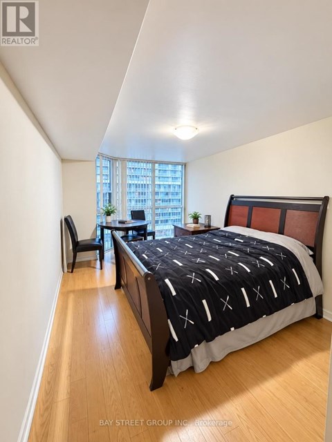 A bedroom with a large bed and a window overlooking a cityscape.