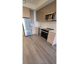 A kitchen with a refrigerator, oven, and microwave.