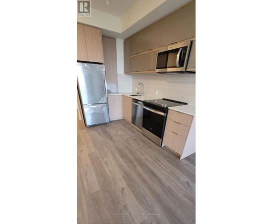 A kitchen with a refrigerator, oven, and microwave.
