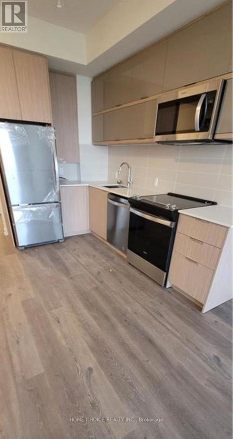 A kitchen with a refrigerator, oven, and microwave.