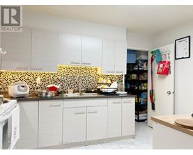 A kitchen with white cabinets and a black and white tiled backsplash.