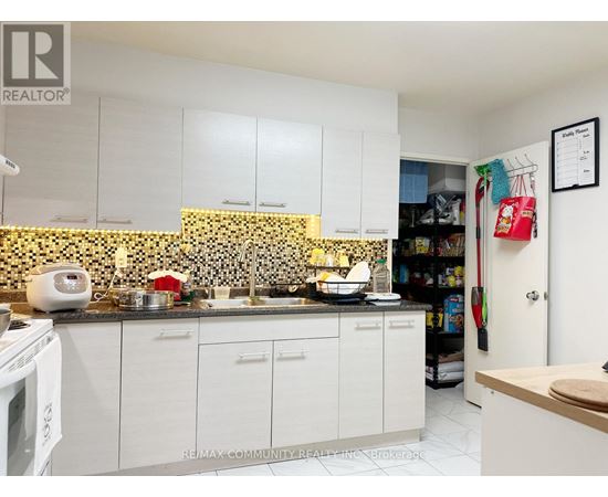 A kitchen with white cabinets and a black and white tiled backsplash.