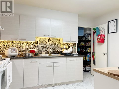 A kitchen with white cabinets and a black and white tiled backsplash.