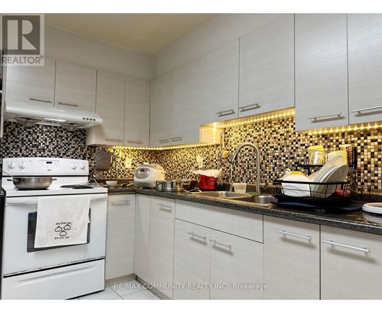 A kitchen with white cabinets and a black and white checkered backsplash.