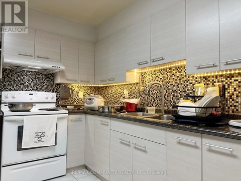 A kitchen with white cabinets and a black and white checkered backsplash.