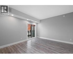 A spacious room with a wooden floor and a sliding glass door leading to a balcony.