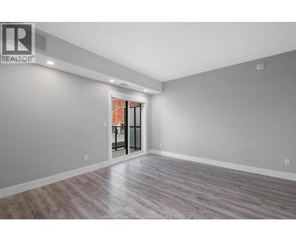 A spacious room with a wooden floor and a sliding glass door leading to a balcony.