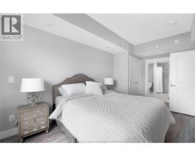 A bedroom with a large bed and a nightstand with a lamp.