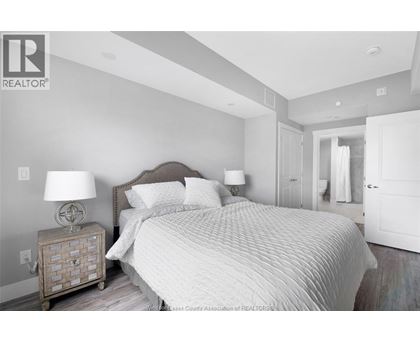 A bedroom with a large bed and a nightstand with a lamp.
