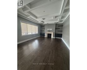 A spacious room with wooden flooring and a large window with blinds.