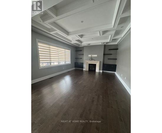 A spacious room with wooden flooring and a large window with blinds.