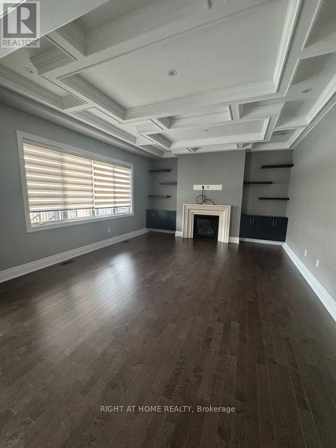 A spacious room with wooden flooring and a large window with blinds.