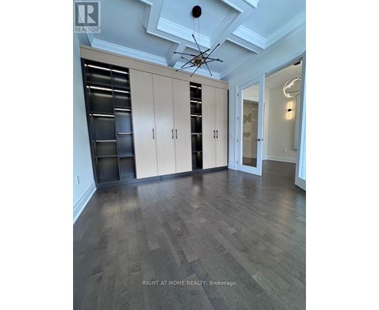 A spacious room with wooden floors and a ceiling fan.