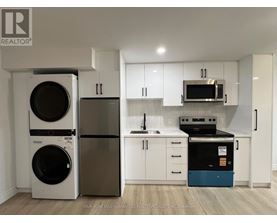 A white kitchen with a washer and dryer on the left and a dishwasher and oven on the right.