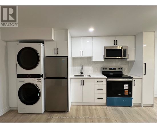 A white kitchen with a washer and dryer on the left and a dishwasher and oven on the right.