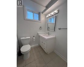 A white bathroom with a toilet, sink, and mirror.