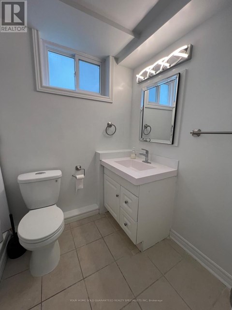 A white bathroom with a toilet, sink, and mirror.