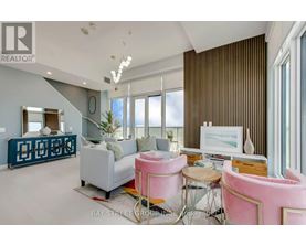 A living room with a pink chair and a white couch.