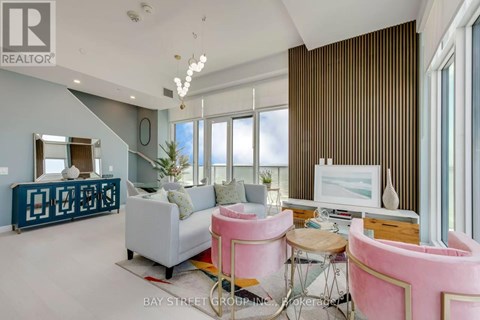 A living room with a pink chair and a white couch.