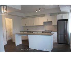 A kitchen with white cabinets and a stainless steel refrigerator.
