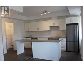 A kitchen with white cabinets and a refrigerator.