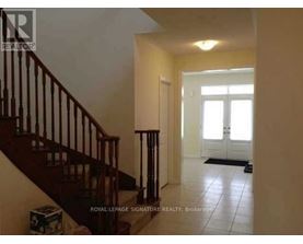 A hallway with a staircase and a door at the end.