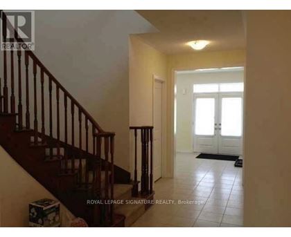 A hallway with a staircase and a door at the end.