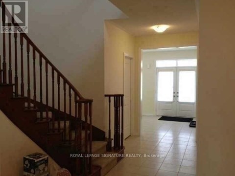 A hallway with a staircase and a door at the end.
