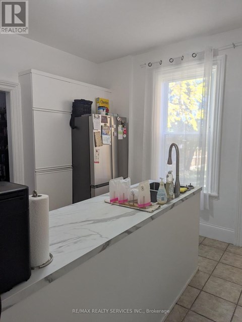 A kitchen with a white counter top and a refrigerator.