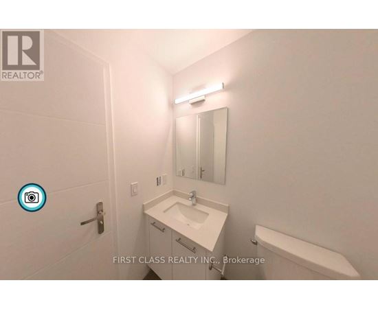 A white sink in a bathroom with a mirror and a light above it.