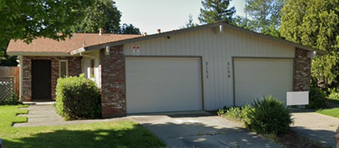 A two-car garage is attached to a brick house.