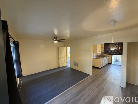 A spacious room with a ceiling fan and a large window.