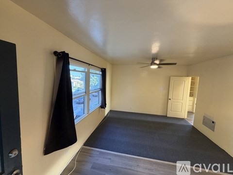 A room with a ceiling fan and a window with a black curtain.