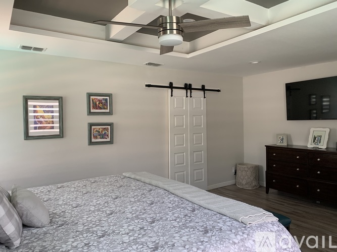 A bedroom with a bed, dresser, and sliding door.