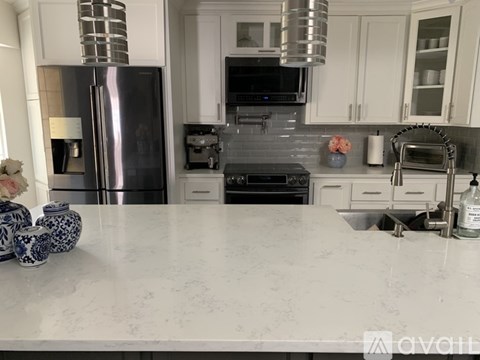 A kitchen with a marble countertop and stainless steel appliances.