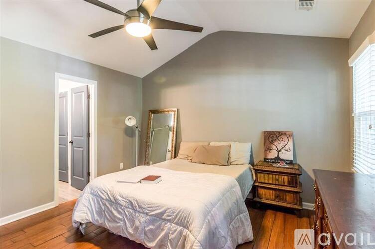 A bedroom with a bed, dresser, mirror, and a ceiling fan.