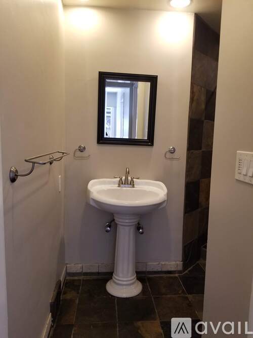 A white pedestal sink in a small bathroom.