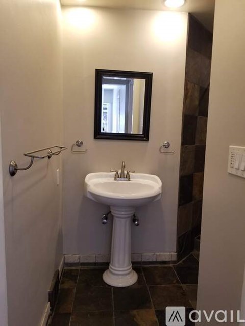 A white pedestal sink in a small bathroom.