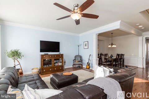 A living room with a brown leather couch and a ceiling fan.