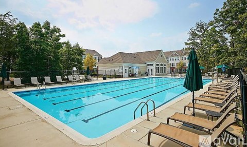 A large outdoor swimming pool surrounded by sun loungers and trees.