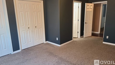 A room with carpeted floor and three doors.
