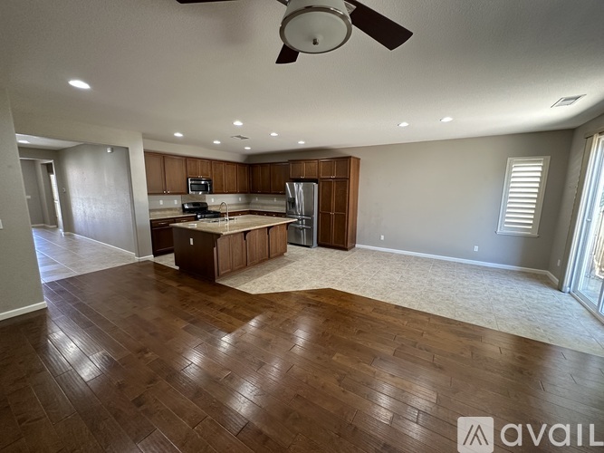 A spacious living room with wooden flooring and a ceiling fan.