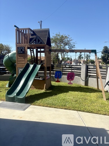 A playground with a green slide and a wooden structure.