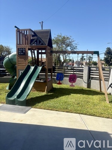 A playground with a green slide and a wooden structure.