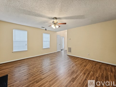 A spacious room with wooden floors and a ceiling fan.