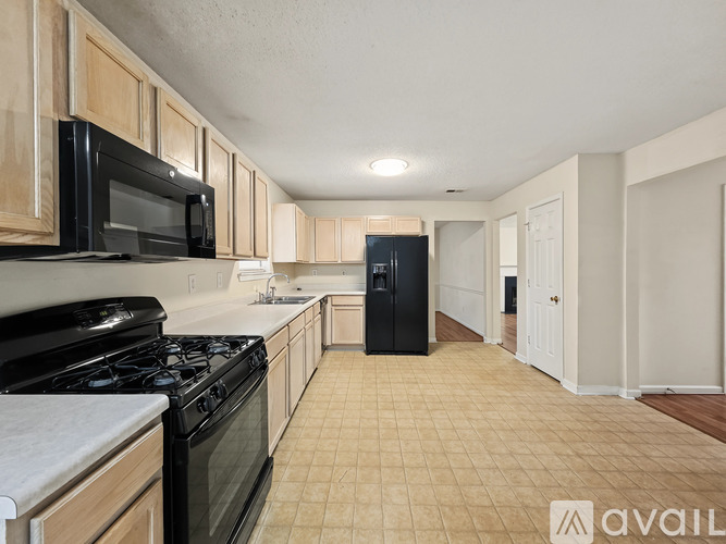 A kitchen with a black fridge and black stove top oven.