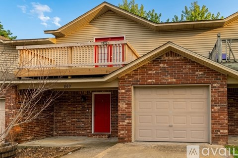 A house with a red door and a garage door is for sale.