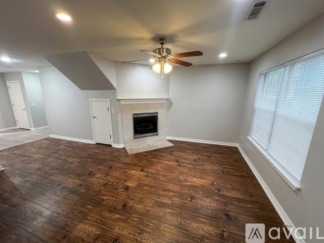 A room with a fireplace and wood flooring.
